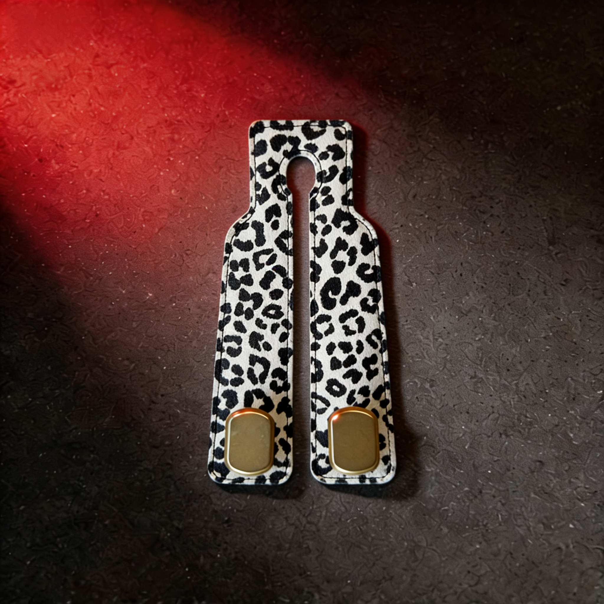 White leopard print faux leather car headrest hook with gold accents on dark surface