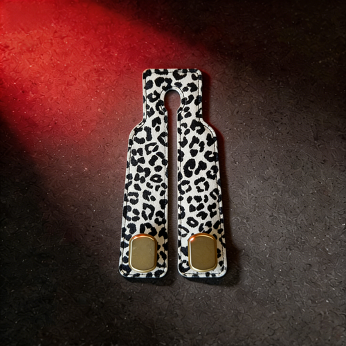 White leopard print faux leather car headrest hook with gold accents on dark surface
